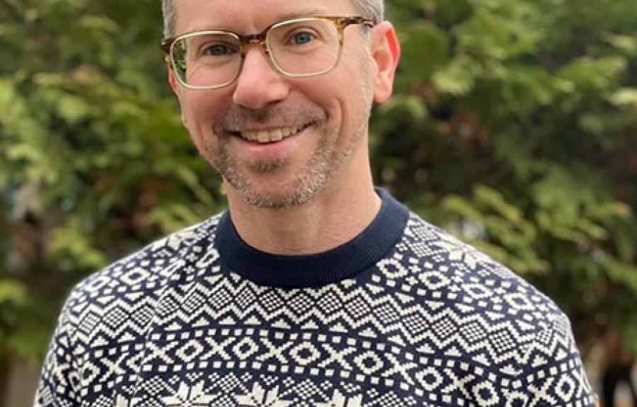 Man in glasses and fair isle sweater with tree in background