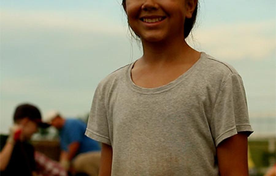 Screenshot from Isabelle&#039;s Garden - a young girl smiles as she stands in a garden.