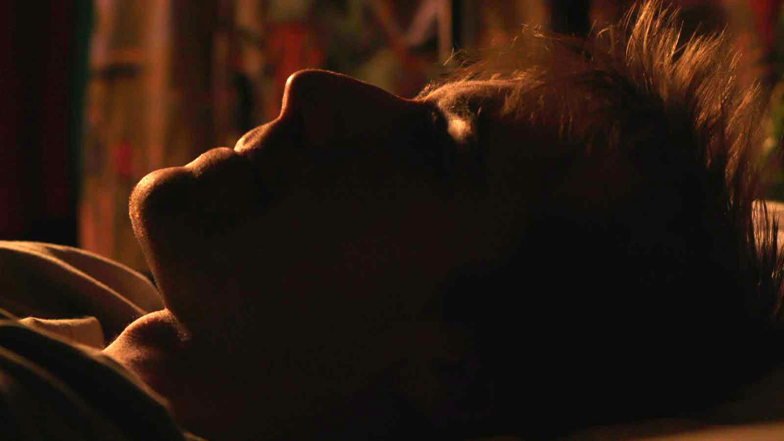 A man lying in bed starring up at the ceiling.