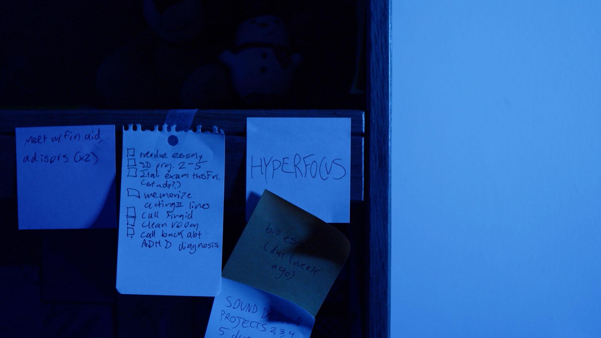 Several square pieces of paper with hand written notes on them taped to a desk's edge.