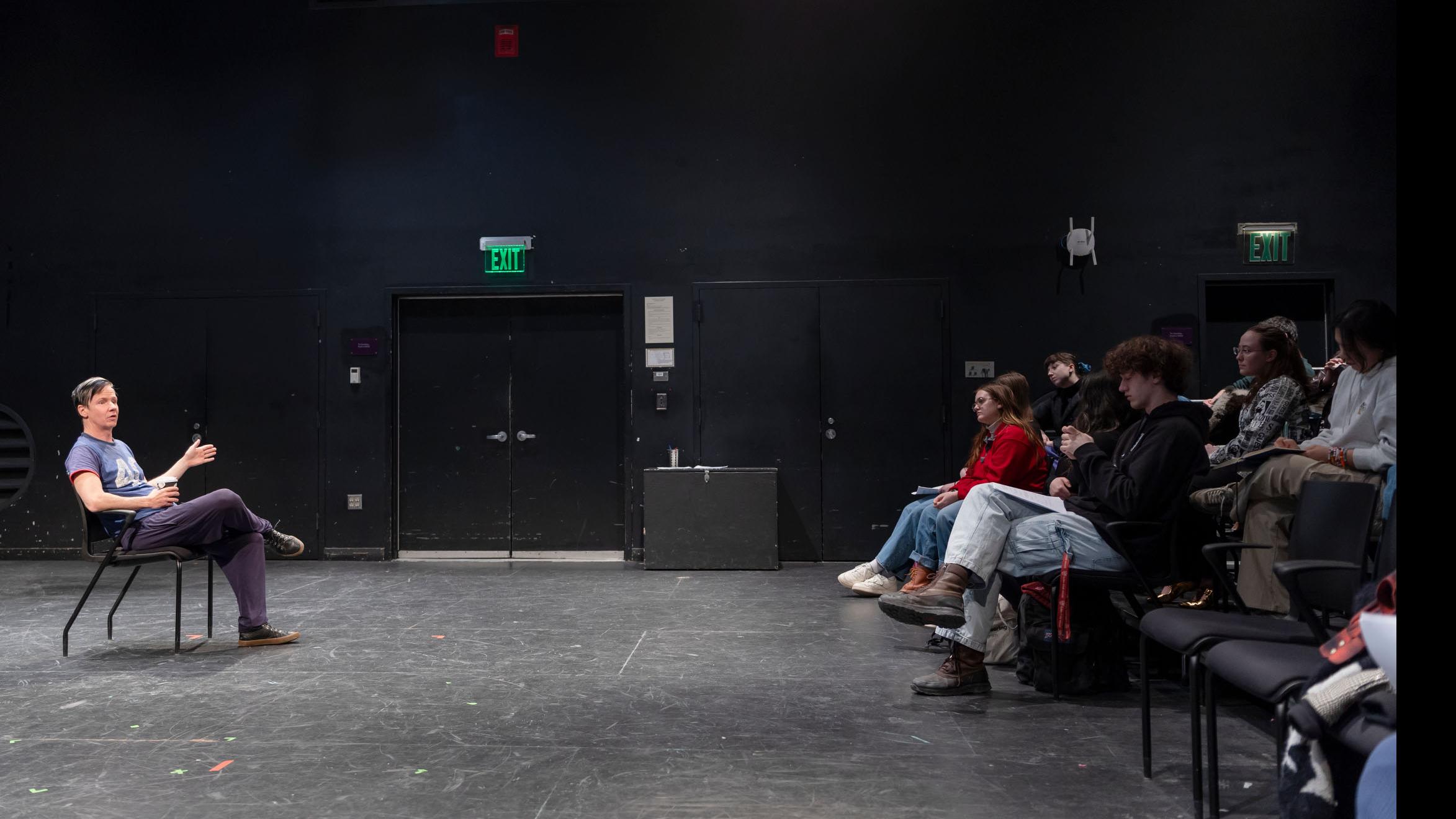 John Cameron Mitchell sits on stage in the Black Box Theatre and speaks to a group of students who sit in the audience. Photo credit: Simon Wheeler
