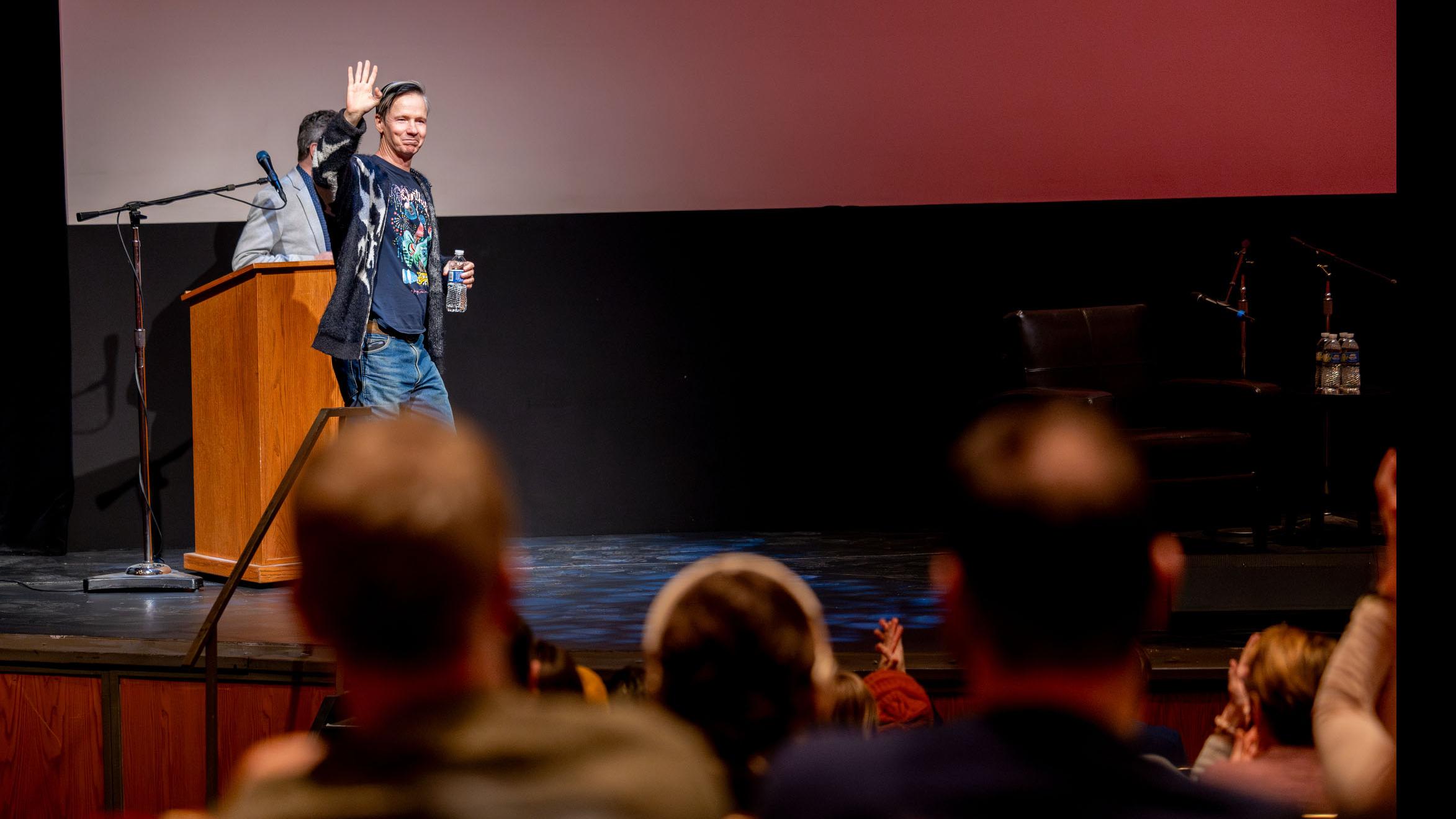 John Cameron Mitchell walks onto the stage in the Kiplinger Theatre, while a crowd of people look on. Photo credit: Simon Wheeler