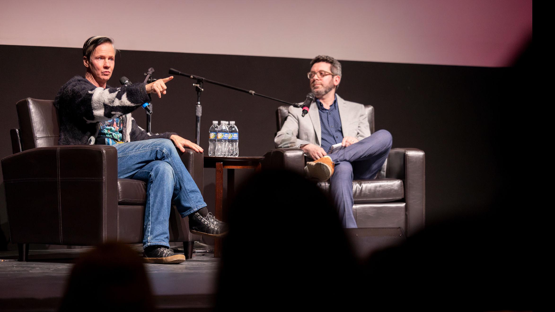 John Cameron Mitchell points into the audience while PMA faculty member Nick Salvato looks over, on stage in the Kiplinger Theatre. Photo credit: Simon Wheeler
