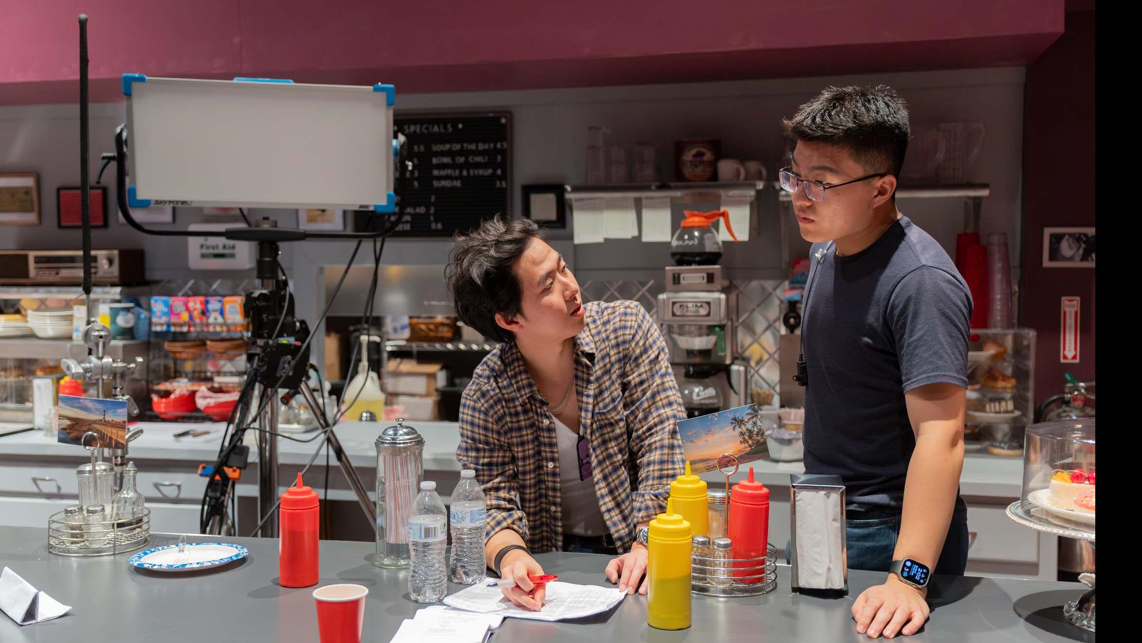 Two student crew members talk over the countertop on the set of the PMA Studios short film Milkshake Kiss. Photo credit: Simon Wheeler