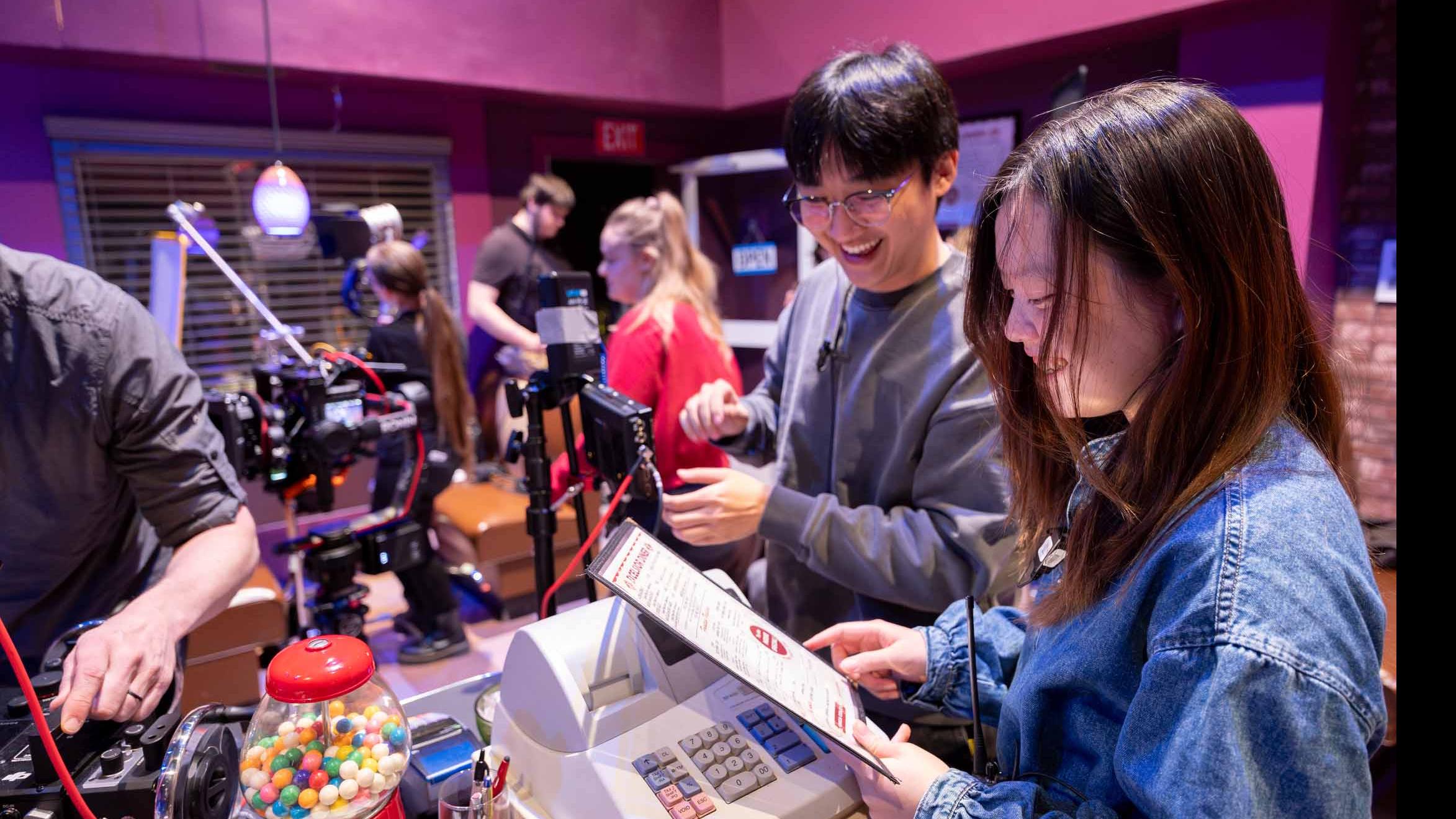 Student crew members look at a menu behind a countertop on the set of the PMA Studios short film Milkshake Kiss. Photo credit: Simon Wheeler