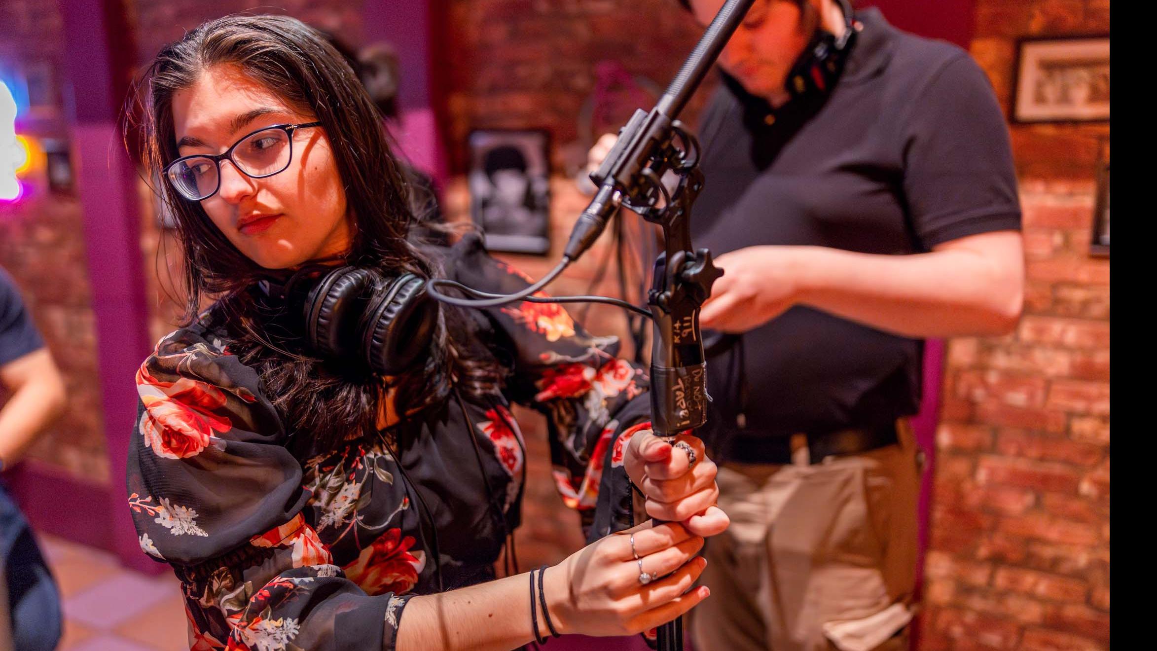 A student crew member adjusts a microphone stand on the set of the PMA Studios short film Milkshake Kiss. Photo credit: Simon Wheeler