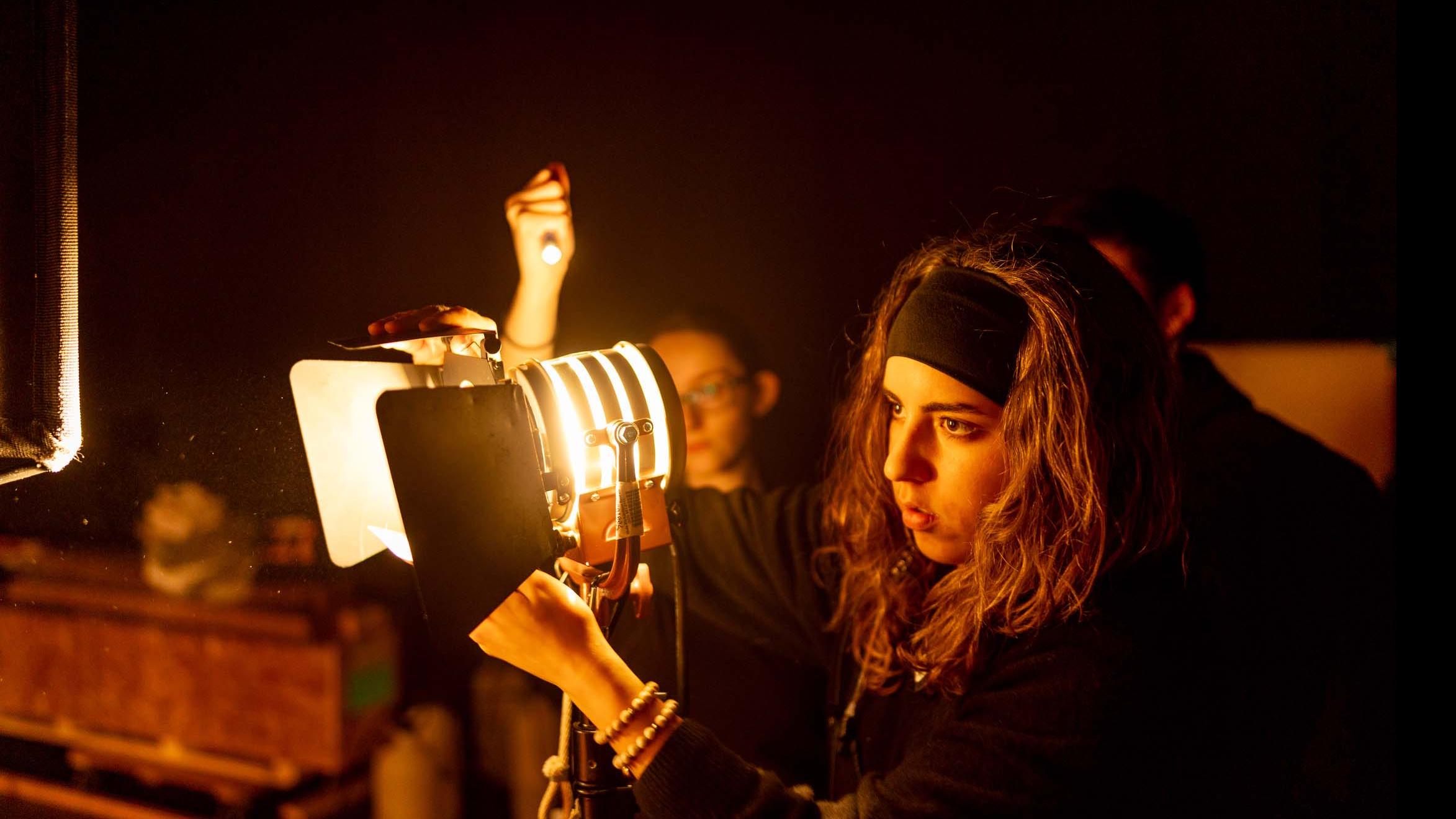 A student crew member adjusts a spotlight on the set of the PMA Studios short film Milkshake Kiss. Photo credit: Simon Wheeler