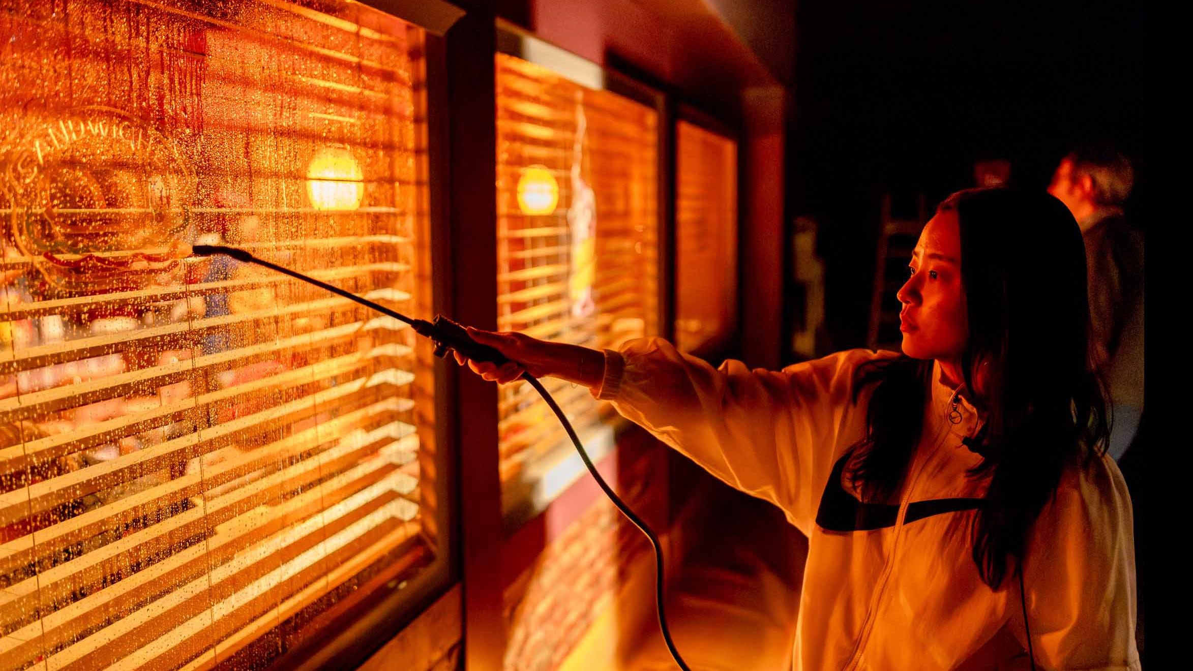 A student crew member mists a window on the exterior of the set of the PMA Studios short film Milkshake Kiss. Photo credit: Simon Wheeler