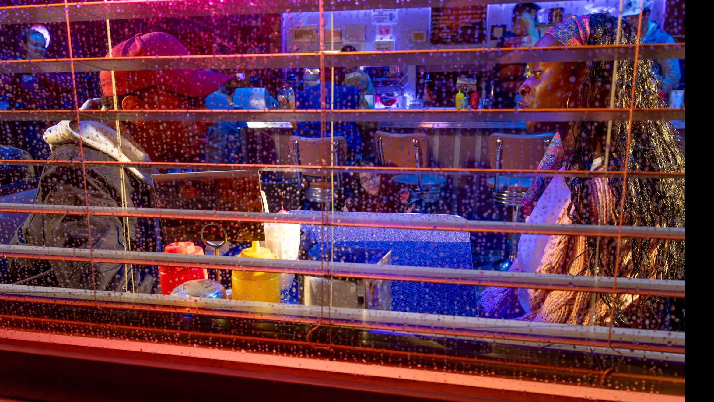 Exterior shot through a window of the set of the PMA Studios short film Milkshake Kiss, where two student actors sit at a diner booth and talk. Photo credit: Simon Wheeler