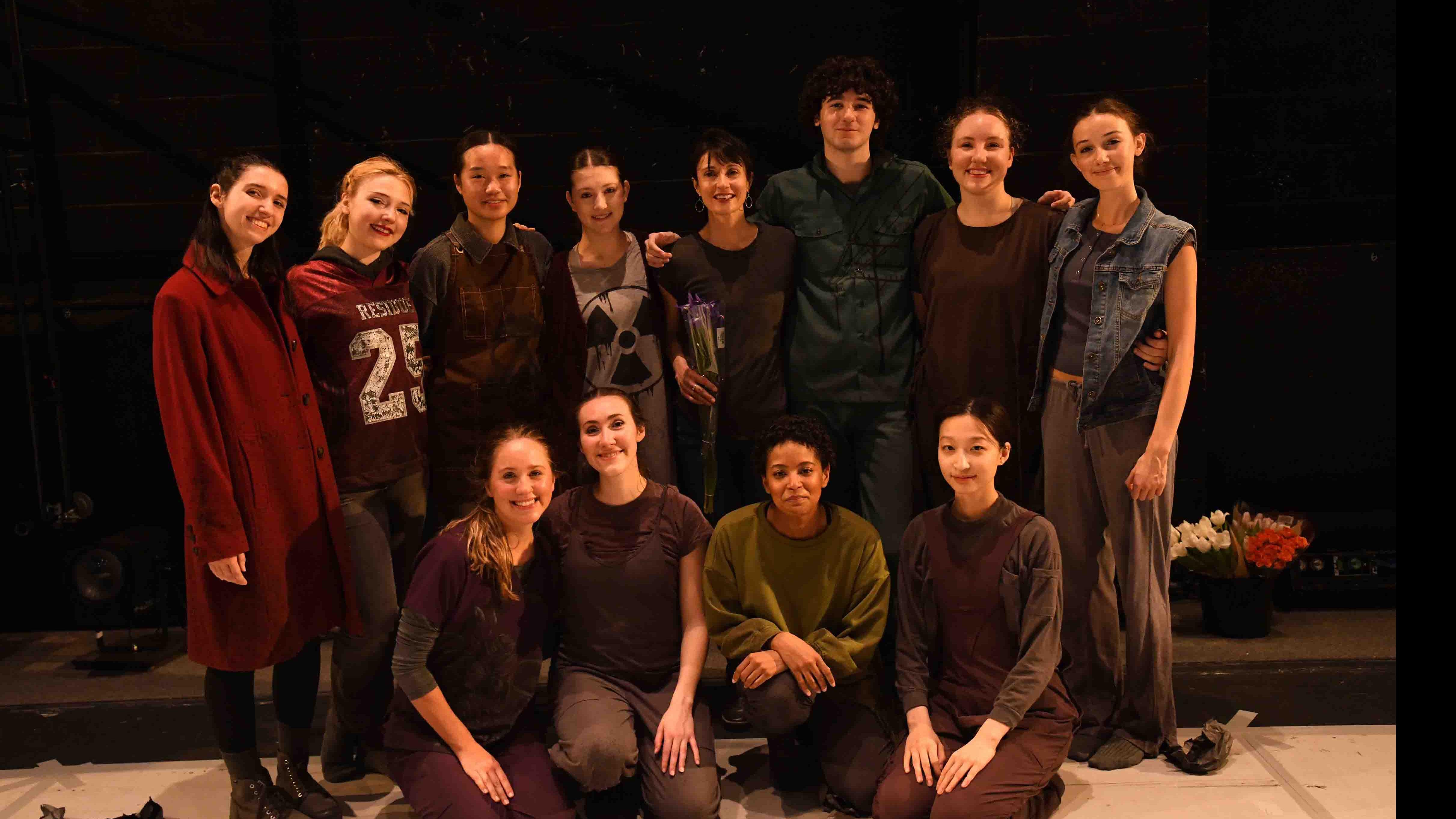 A posed photo of PMA faculty member Olive Prince along with eleven student dancers on stage. Photo credit: Thomas Hoebbel