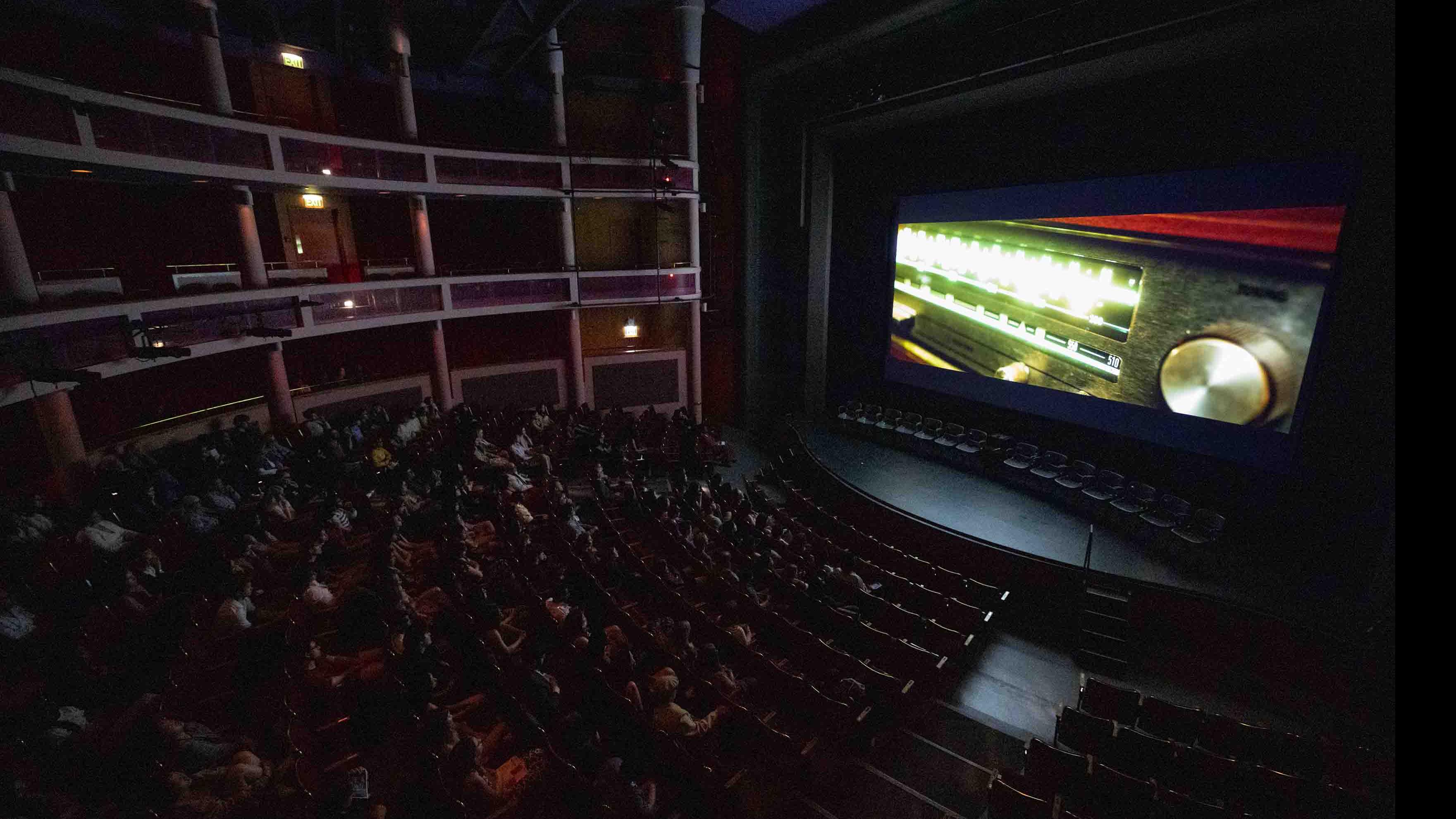 An aerial view of the audience in the Kiplinger Theatre, while the PMA Studios short film Milkshake Kiss plays on a large screen. Photo credit: Chris Kitchen