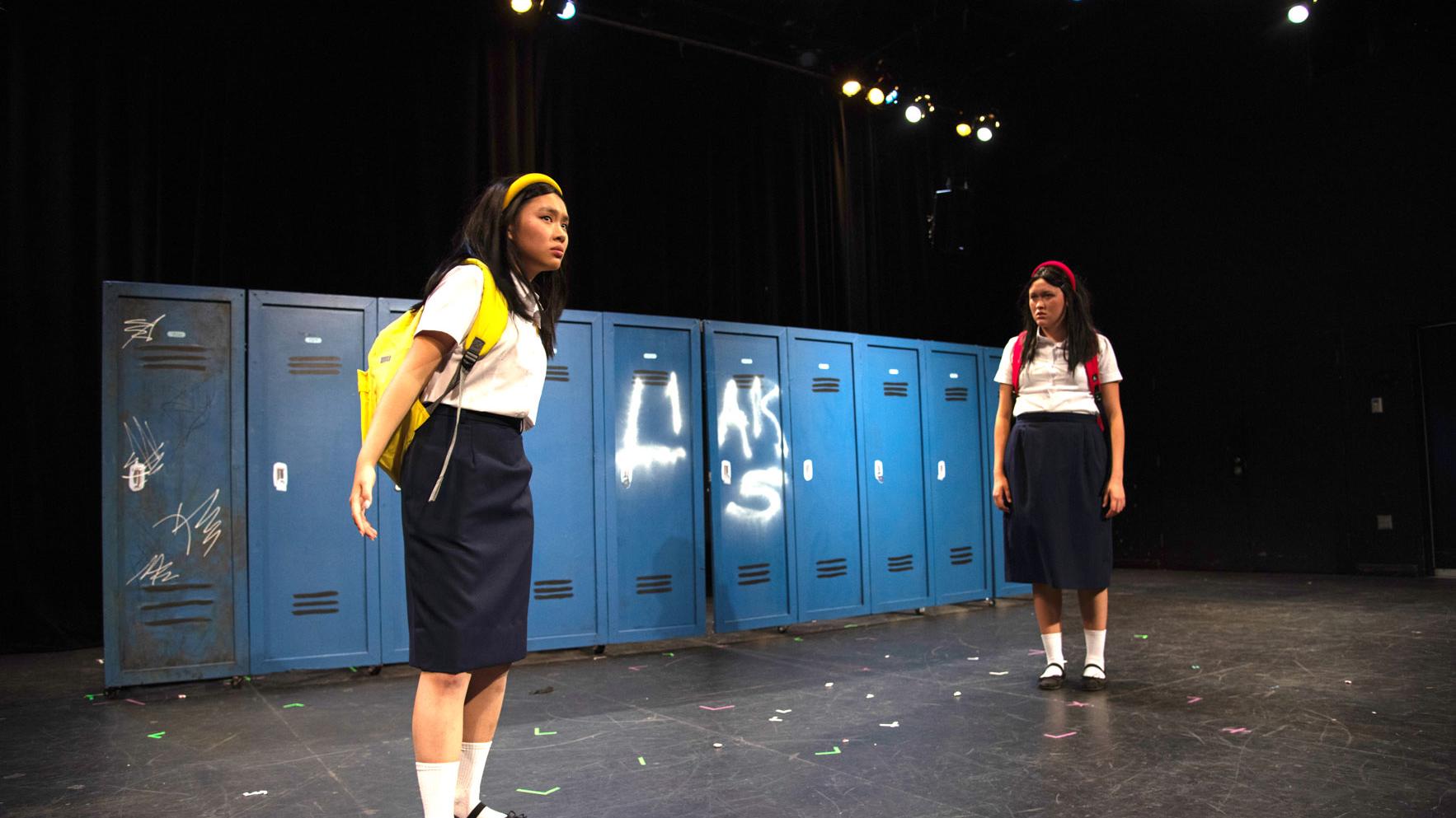 A production photo from a play Peerless. Two actors in school uniforms are rehearsing on stage in the Black Box Theatre