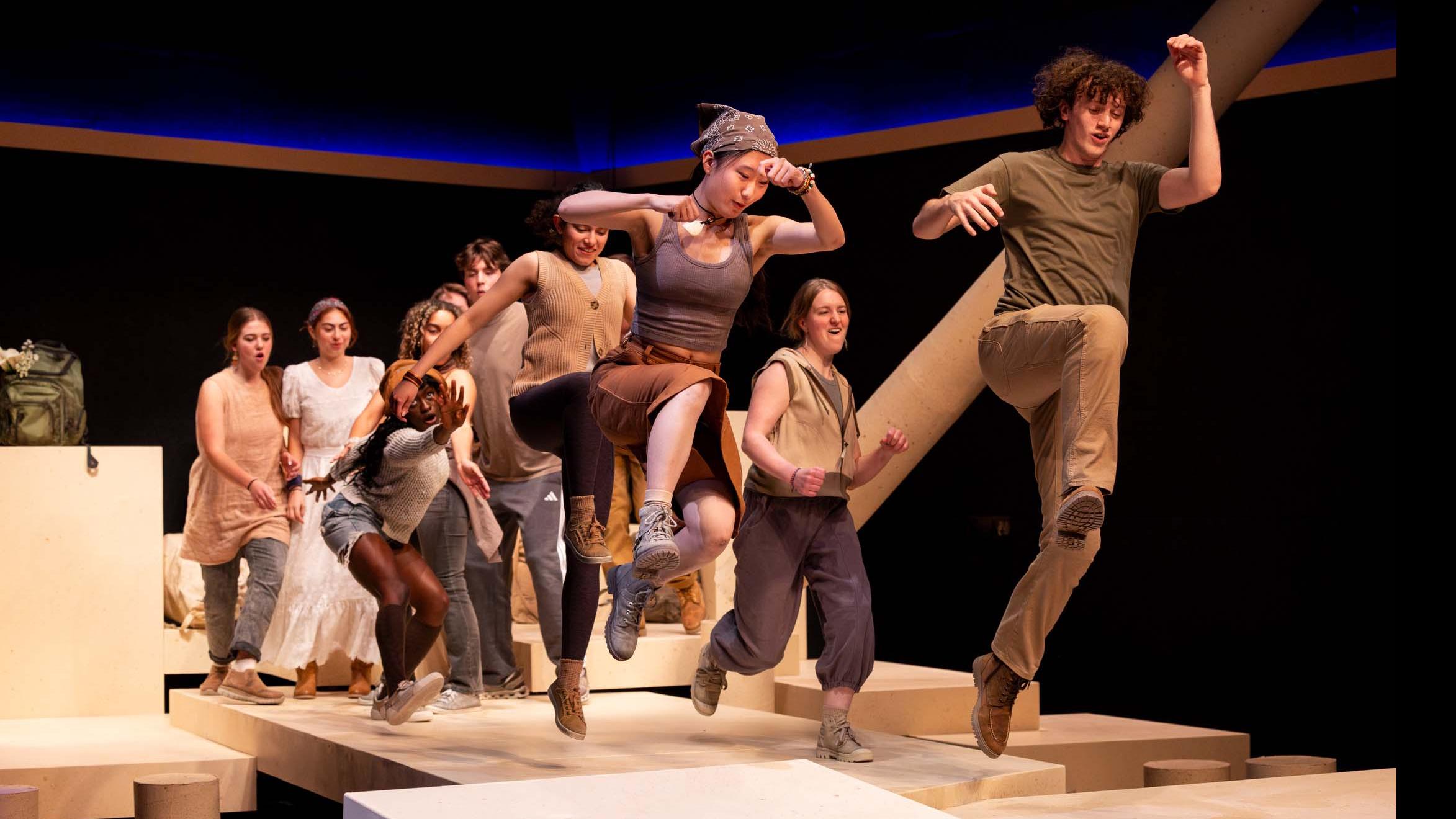 An ensemble of performers run and leap forward during a performance of I Want a Country in the Flex Theatre, Schwartz Center for the Performing Arts.