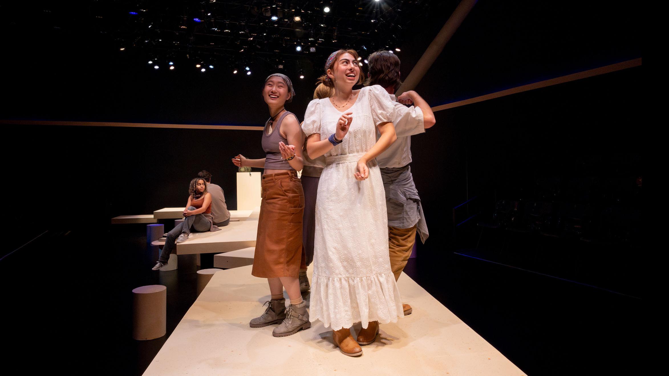 Four cast members smile in a circle during a performance of I Want a Country in the Flex Theatre, Schwartz Center for the Performing Arts.