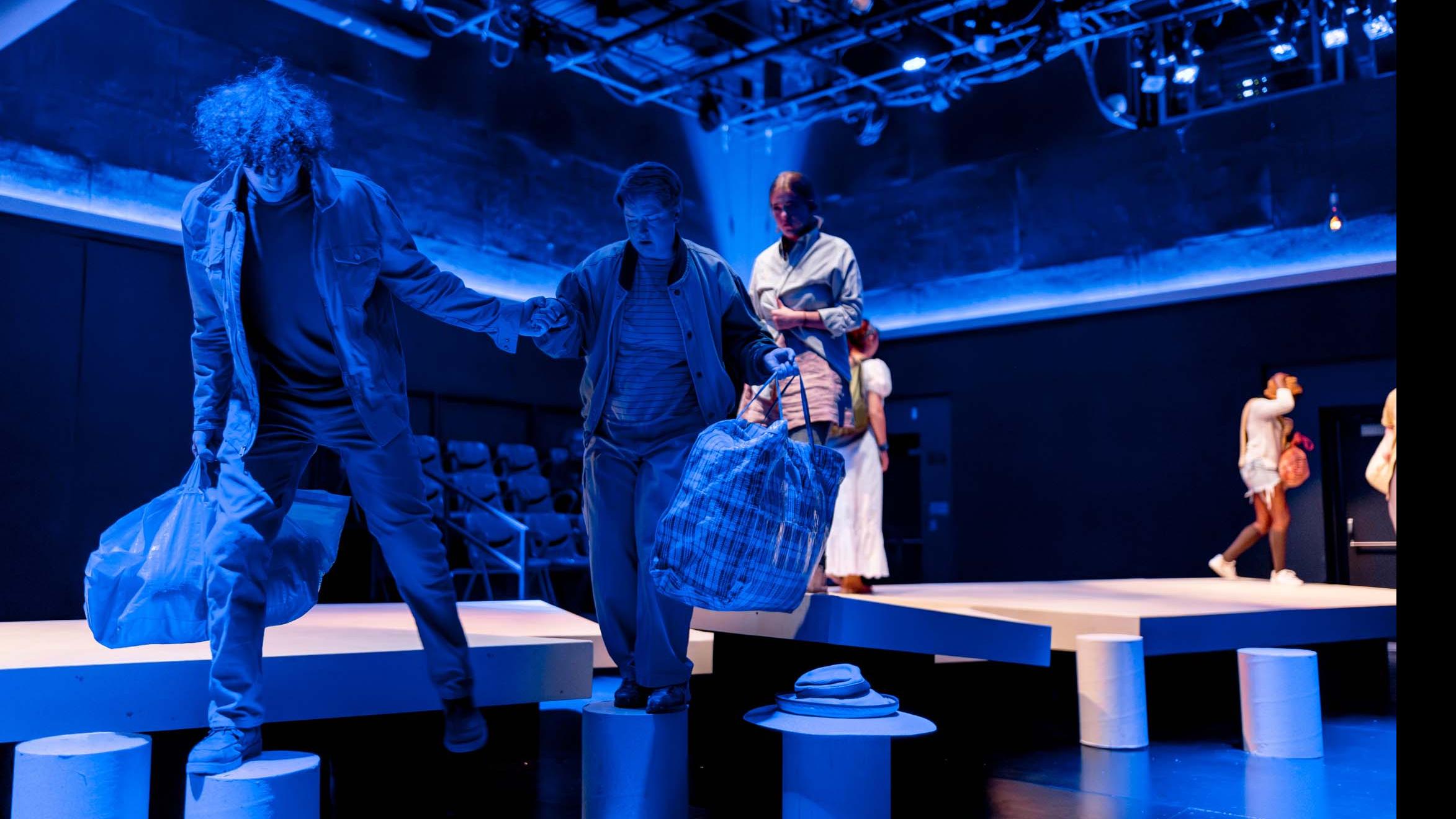 Two cast members step onto cylindrical platforms during a performance of I Want a Country in the Flex Theatre, Schwartz Center for the Performing Arts.