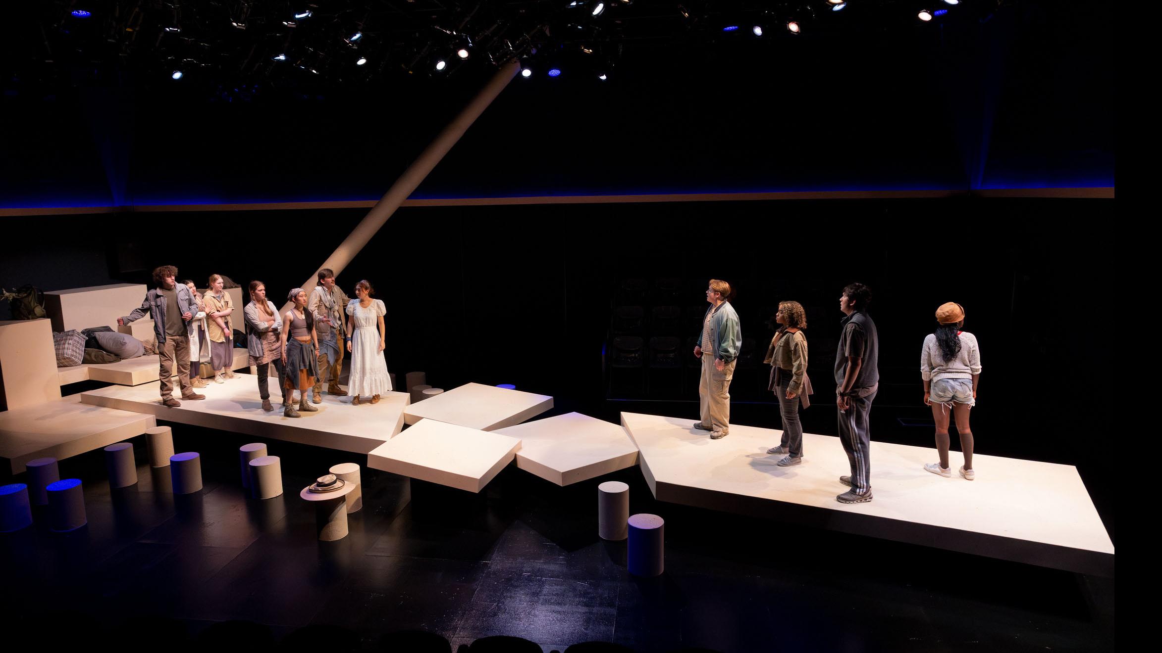 An ensemble of performers stand in two groups on opposite sides of the stage during a performance of I Want a Country in the Flex Theatre, Schwartz Center for the Performing Arts.