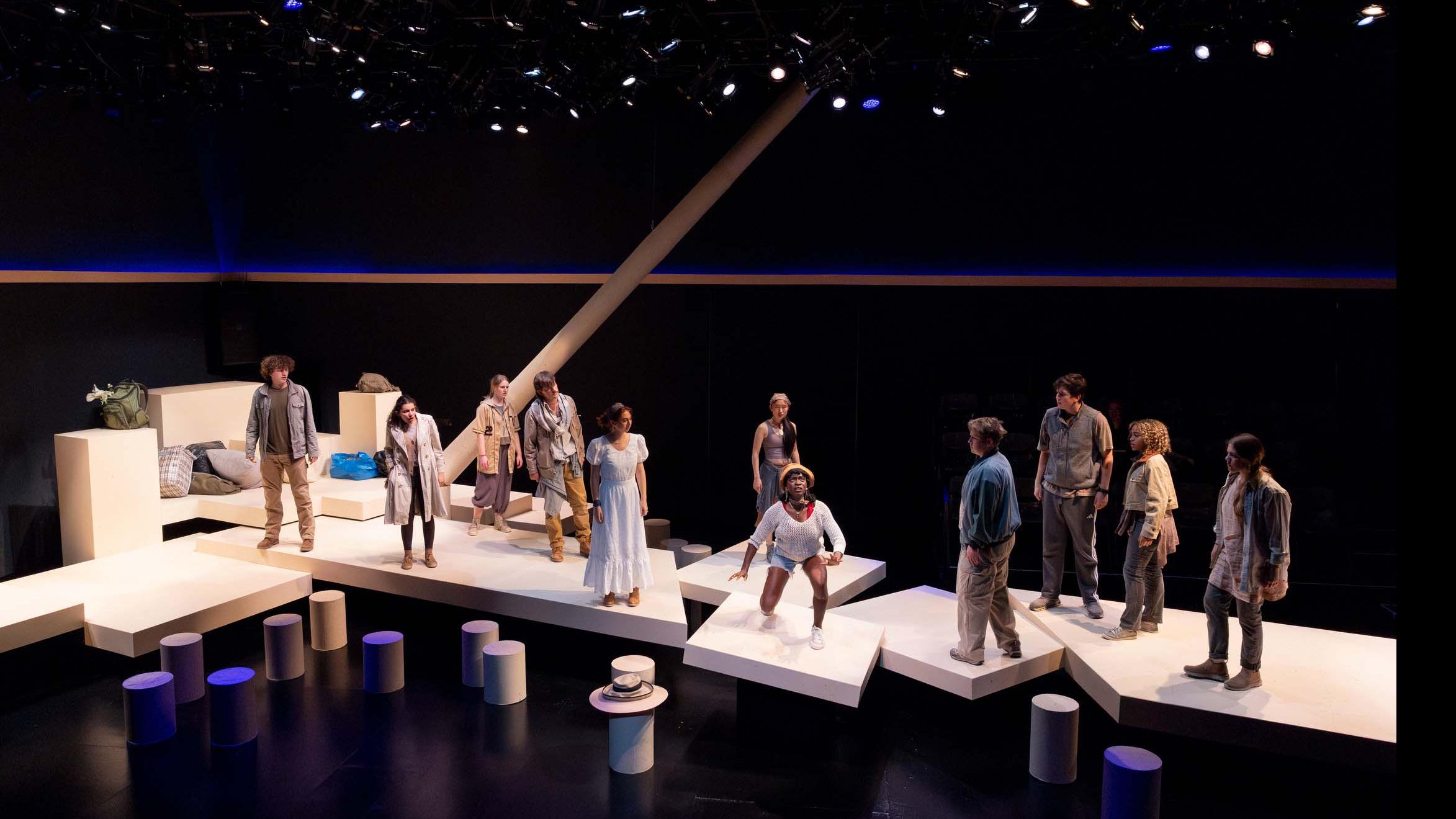 An ensemble of performers spread across the stage look towards a central cast member during a performance of I Want a Country in the Flex Theatre, Schwartz Center for the Performing Arts.