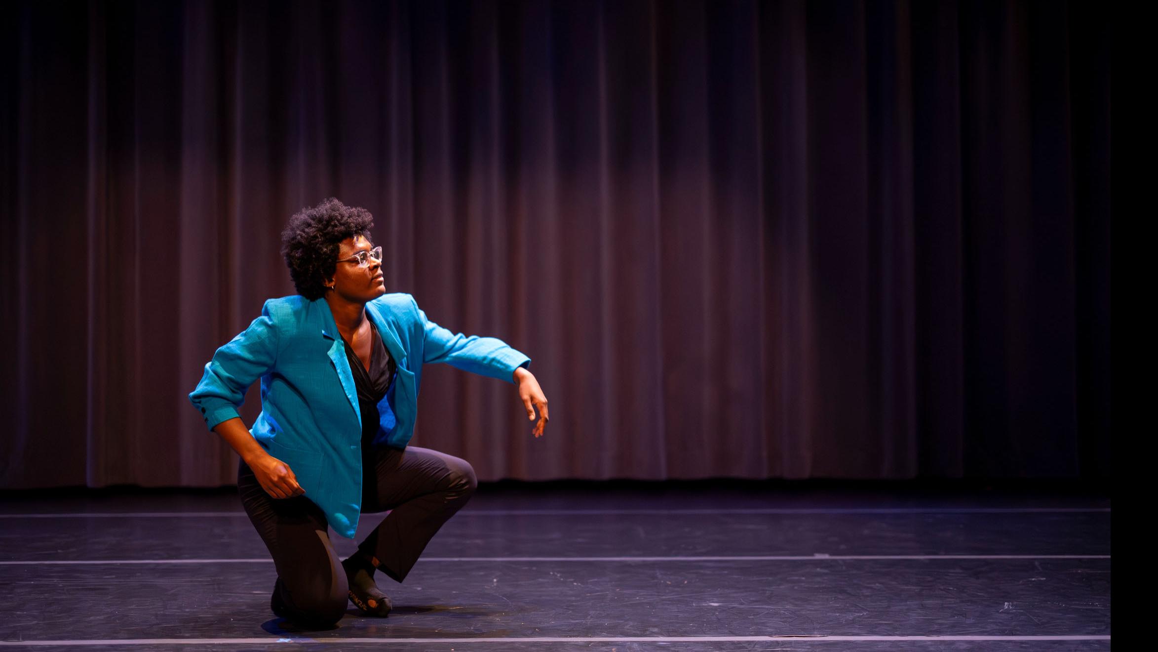 Julia Nwodeki crouches in a movement pose during Share In / Share Out in the Class of ’56 Dance Studio Theatre, Schwartz Center.