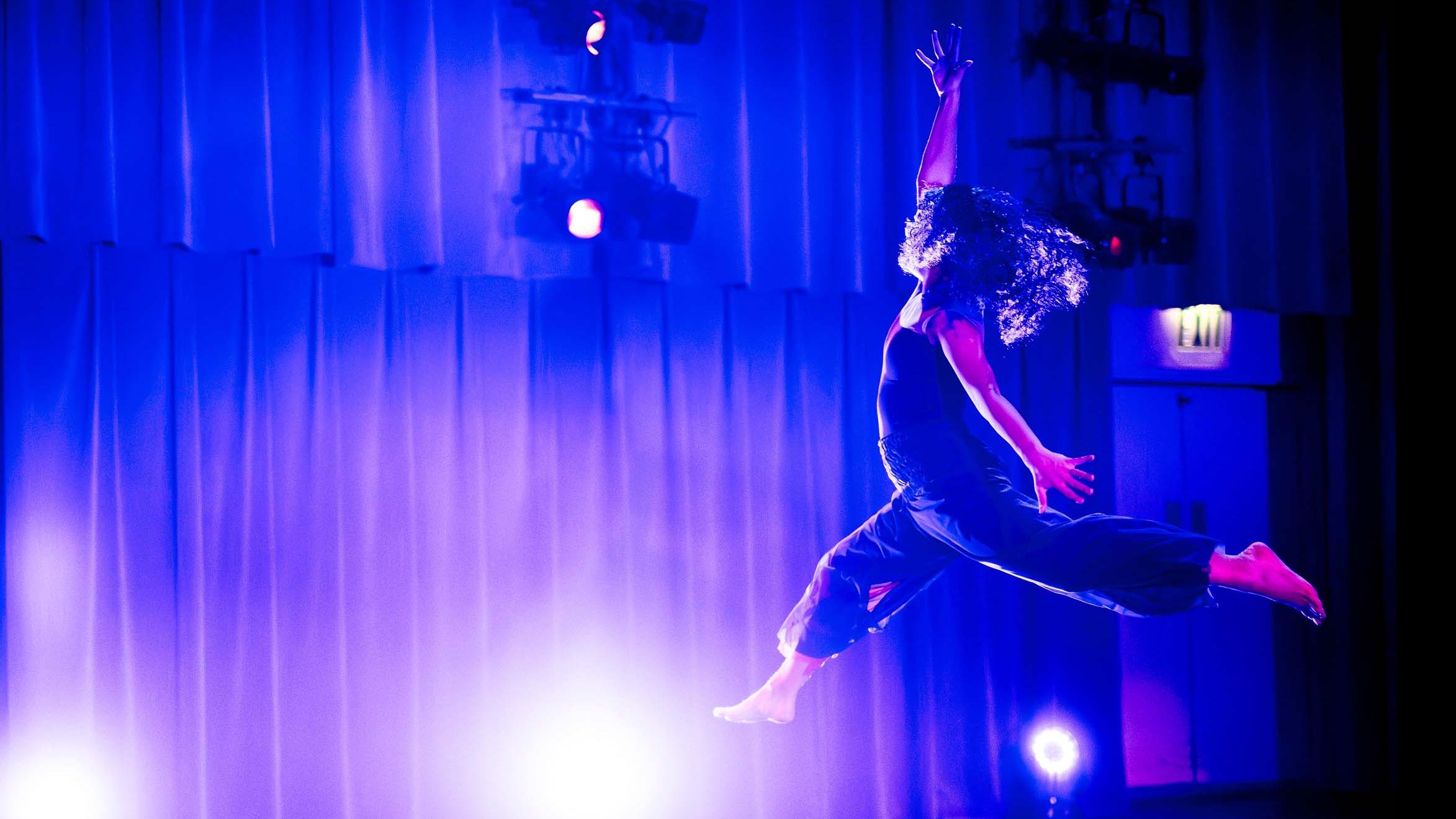 Ashley Padres jumps in a movement pose during Share In / Share Out in the Class of ’56 Dance Studio Theatre, Schwartz Center.