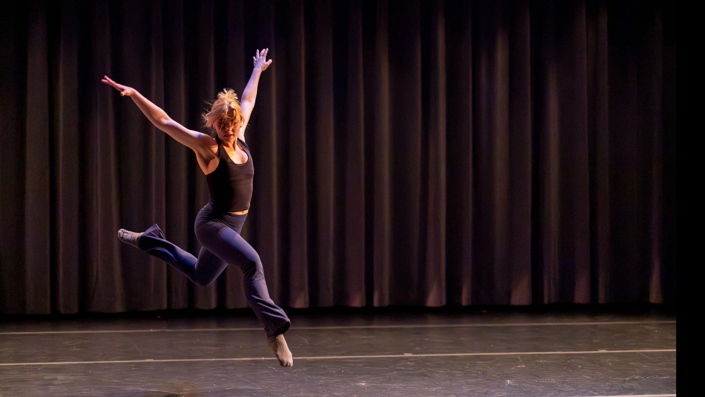 Ashley Dorais jumps in a movement pose during Share In / Share Out in the Class of ’56 Dance Studio Theatre, Schwartz Center.