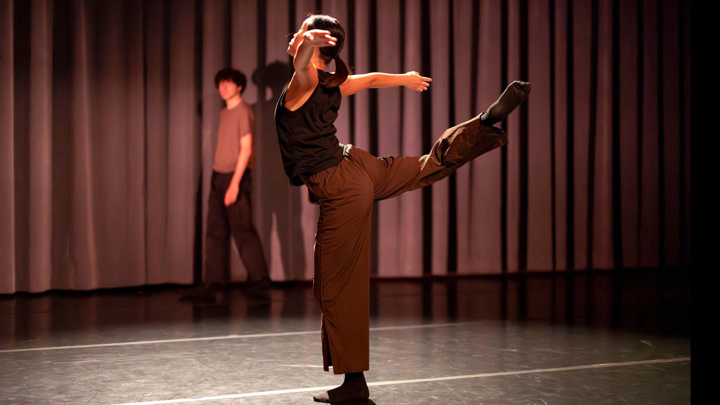 In foreground, Avery Wang, in background Nick DeMayo, in movement poses during Share In / Share Out in the Class of ’56 Dance Studio Theatre, Schwartz Center.