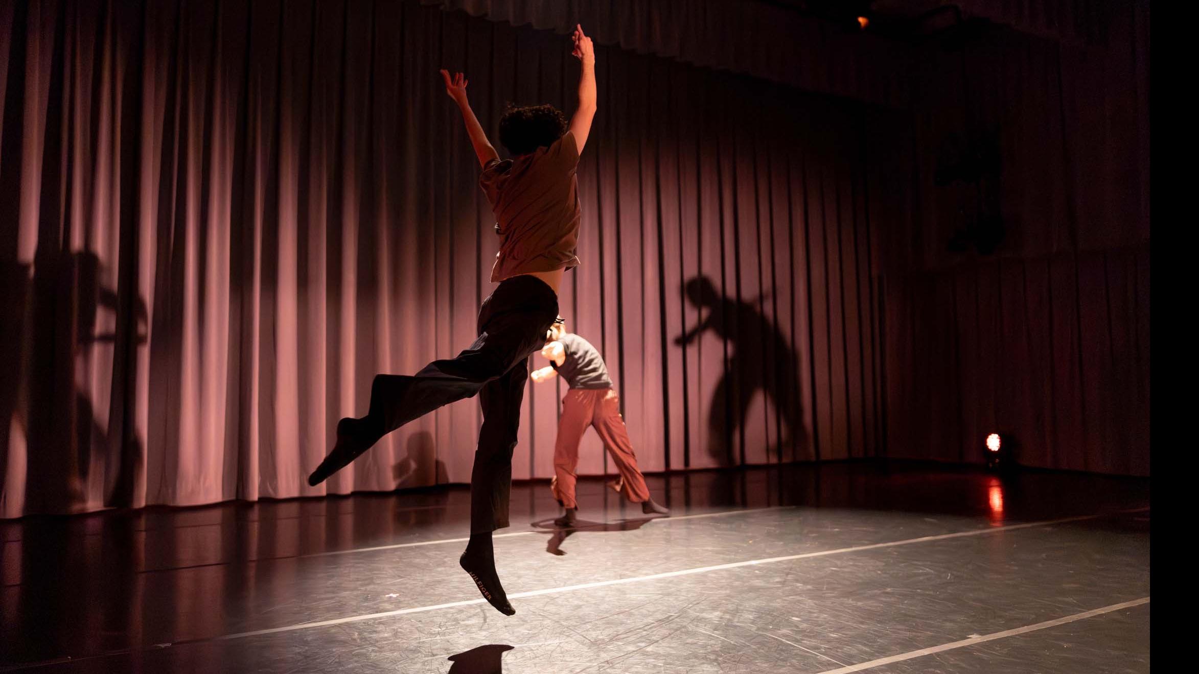 In foreground, Nick DeMayo, in background Avery Wang, in movement poses during Share In / Share Out in the Class of ’56 Dance Studio Theatre, Schwartz Center.
