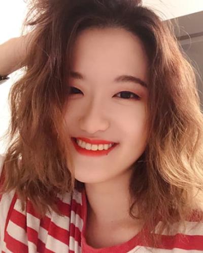 Lyra Liu smiling in a striped shirt with a hand in her hair