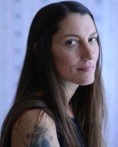 Woman with long brown hair wearing tank top with shoulder tattoo